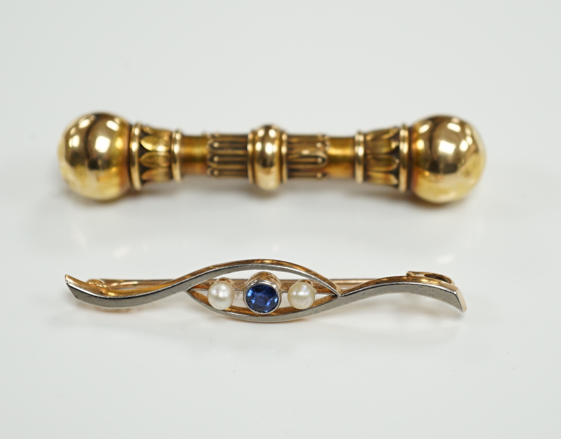 A Victorian yellow metal 'dumbbell' bar brooch, with engraved inscription dated 1862, 56mm and a later 15ct, sapphire and seed pearl set three stone crossover bar brooch.